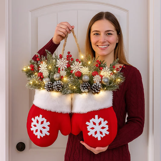 Person holding a Christmas mitten wreath with LED lights shaped like red mittens with white snowflakes.