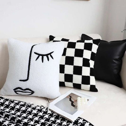 Checkerboard throw pillow styled on bed with blanket