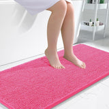 Pink soft chenille bathroom mat placed in front of a bathroom sink on light tile floor