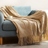 Dark gray coral fleece blanket folded at the foot of a white bed in a modern bedroom