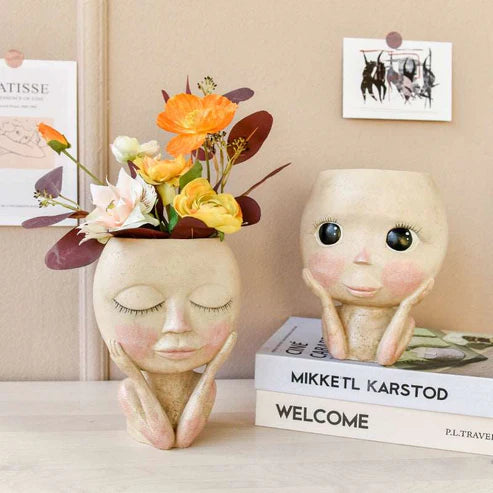 Face head sculpture planter holding fresh yellow flowers