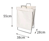 Large foldable fabric laundry hamper sitting on a closet floor holding sorted clothes