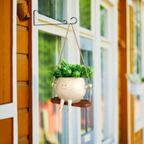 Hanging face planter hung on garden fence with plant