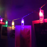 Colorful LED photo holder string lights displaying photos on wall