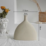 Matte ceramic vase with dried eucalyptus stems on a dining table in a minimalist room