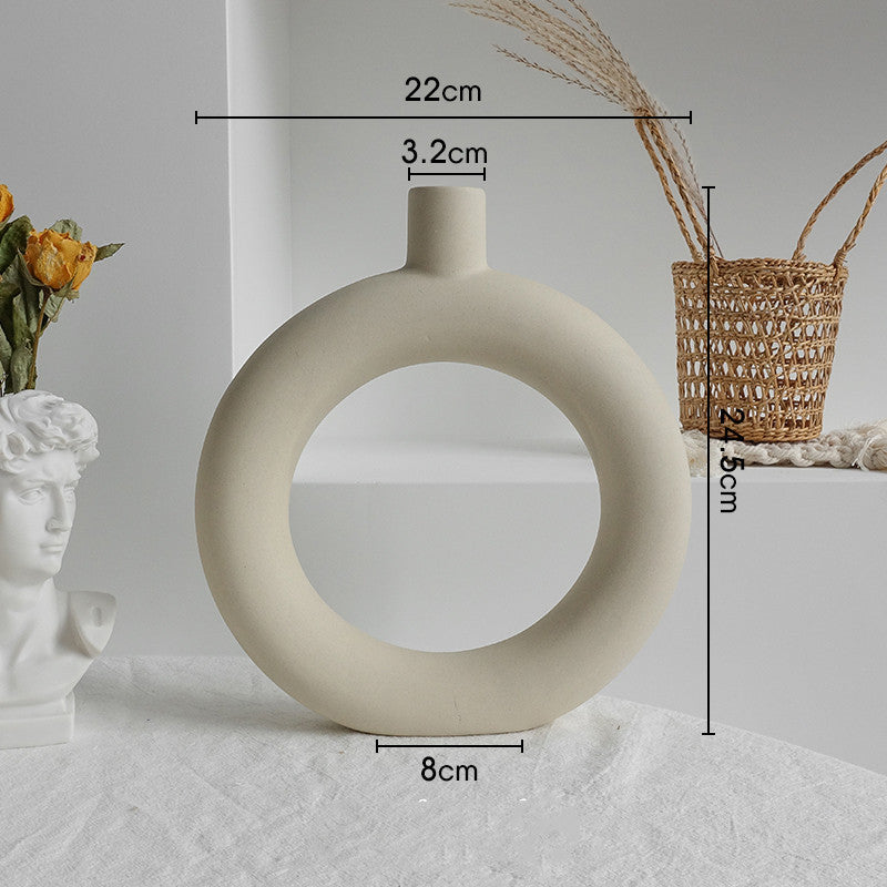Matte ceramic vase with a dried decorative branch on a home office desk beside a laptop