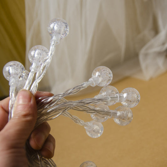 Hand holding Splendas LED crystal ball fairy string lights showing ball size and detail