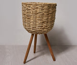 Woven straw floor planter in a Nordic minimalist living room with white walls and wood furniture