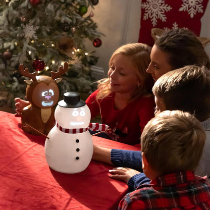 Family gathered around a snowman-shaped light with a reindeer decoration in front of a Christmas tree.
