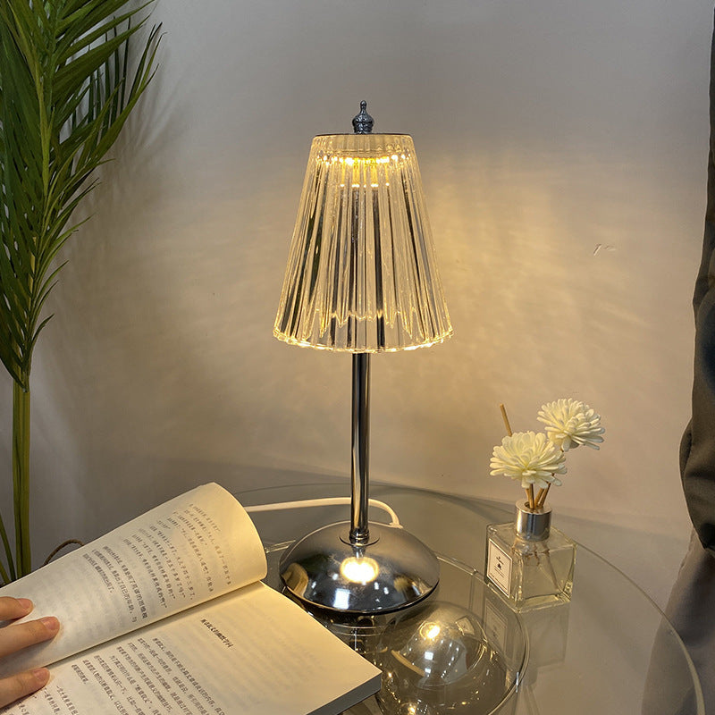Crystal Table lamp on a glass table with an open book and a small plant.