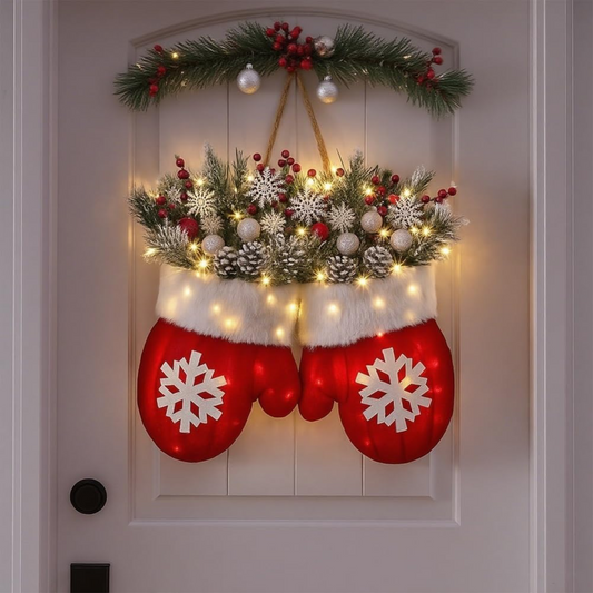 Decorative Christmas door hanger with red mittens, white snowflakes, and festive lights on a white door.