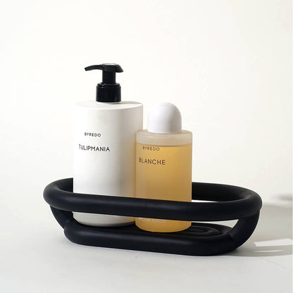 Black resin soap dish and bathroom storage tray set styled together on a white vanity counter
