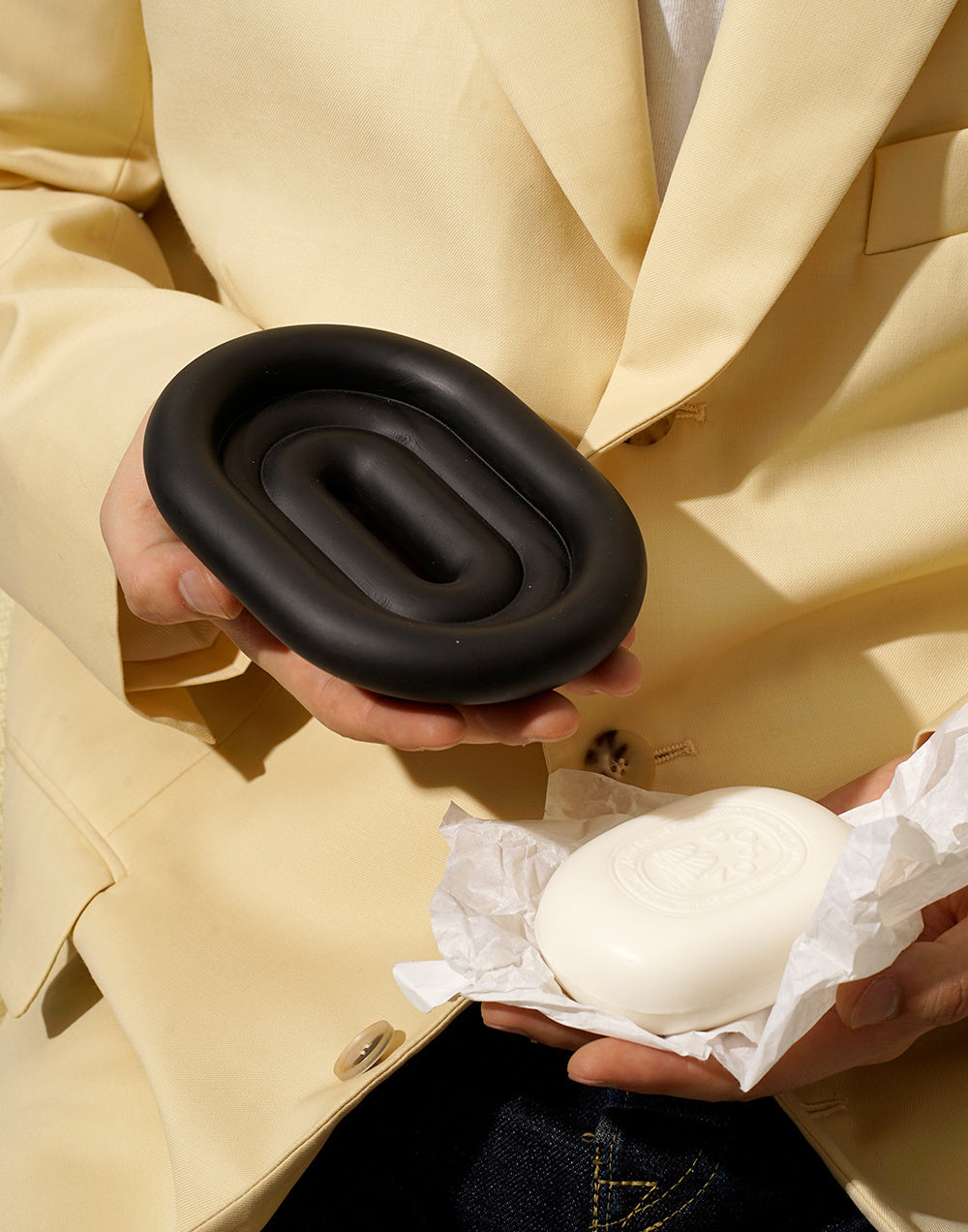 Black resin soap dish and tray set styled in a Nordic minimalist bathroom with white tile
