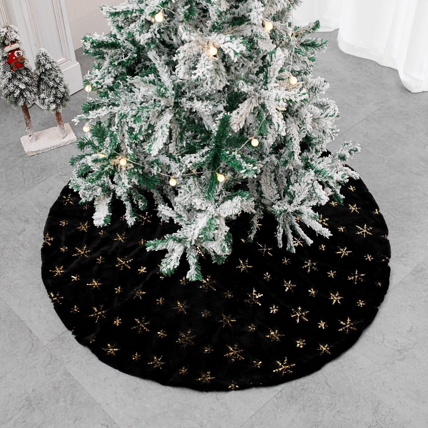 Black velvet Christmas tree skirt placed under decorated holiday tree