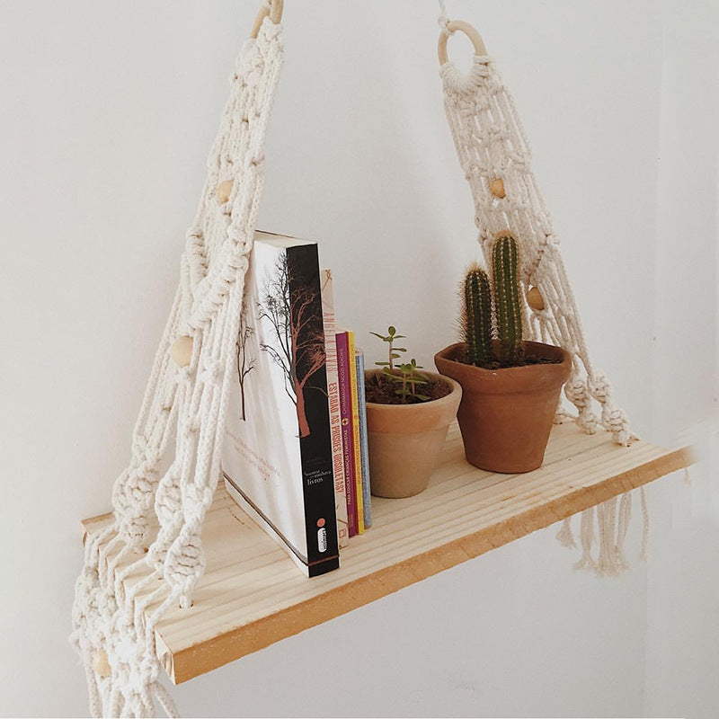 Bohemian wall tapestry shelf styled above a bed with a small plant and candle on the ledge