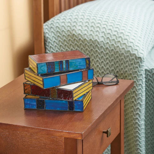 Book stack lamp shown unlit during daytime in bedroom