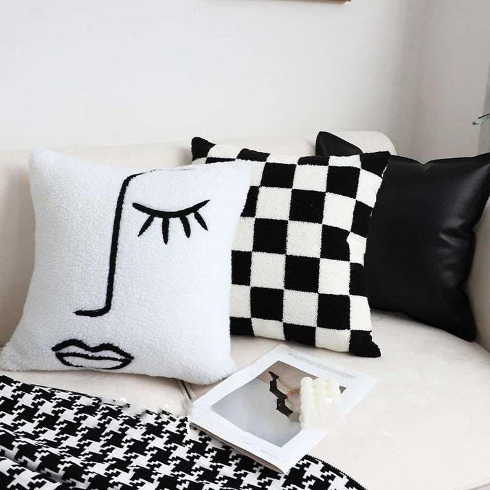 Checkerboard throw pillow styled on bed with blanket