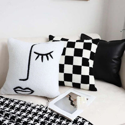 Checkerboard throw pillow styled on bed with blanket