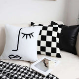 Checkerboard throw pillow styled on bed with blanket