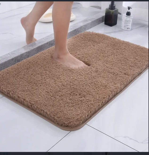 Camel colored chenille floor mat on dark hardwood flooring beside a bathroom vanity
