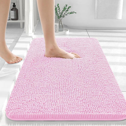 Pink soft chenille bathroom mat placed in front of a bathroom sink on light tile floor
