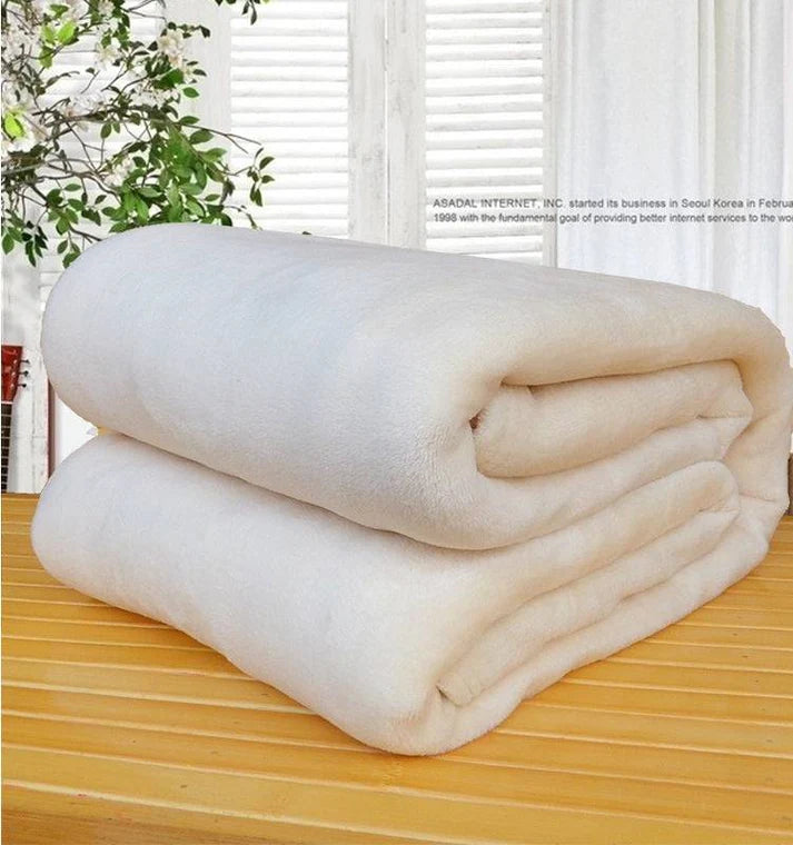 Coral fleece solid color blanket folded in beige on wood table