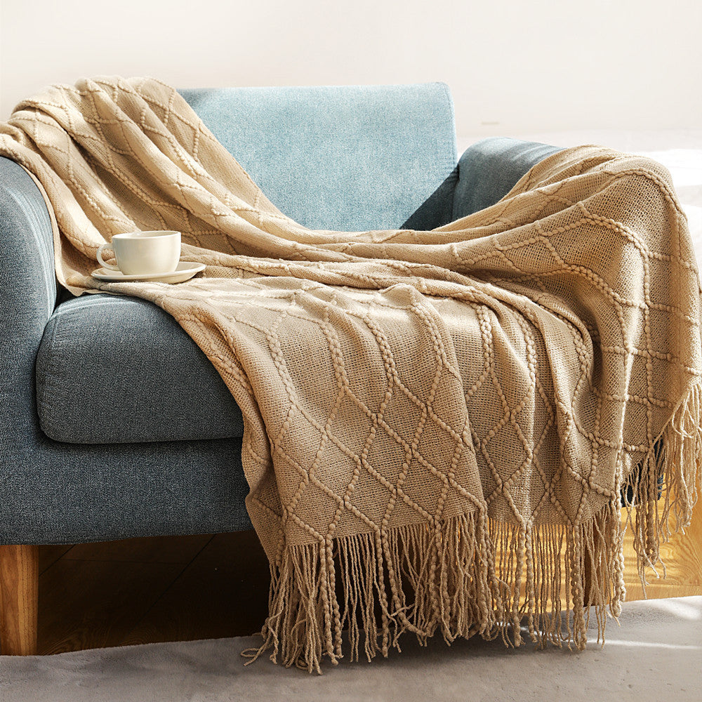 Dark gray coral fleece blanket folded at the foot of a white bed in a modern bedroom
