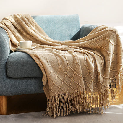 Dark gray coral fleece blanket folded at the foot of a white bed in a modern bedroom
