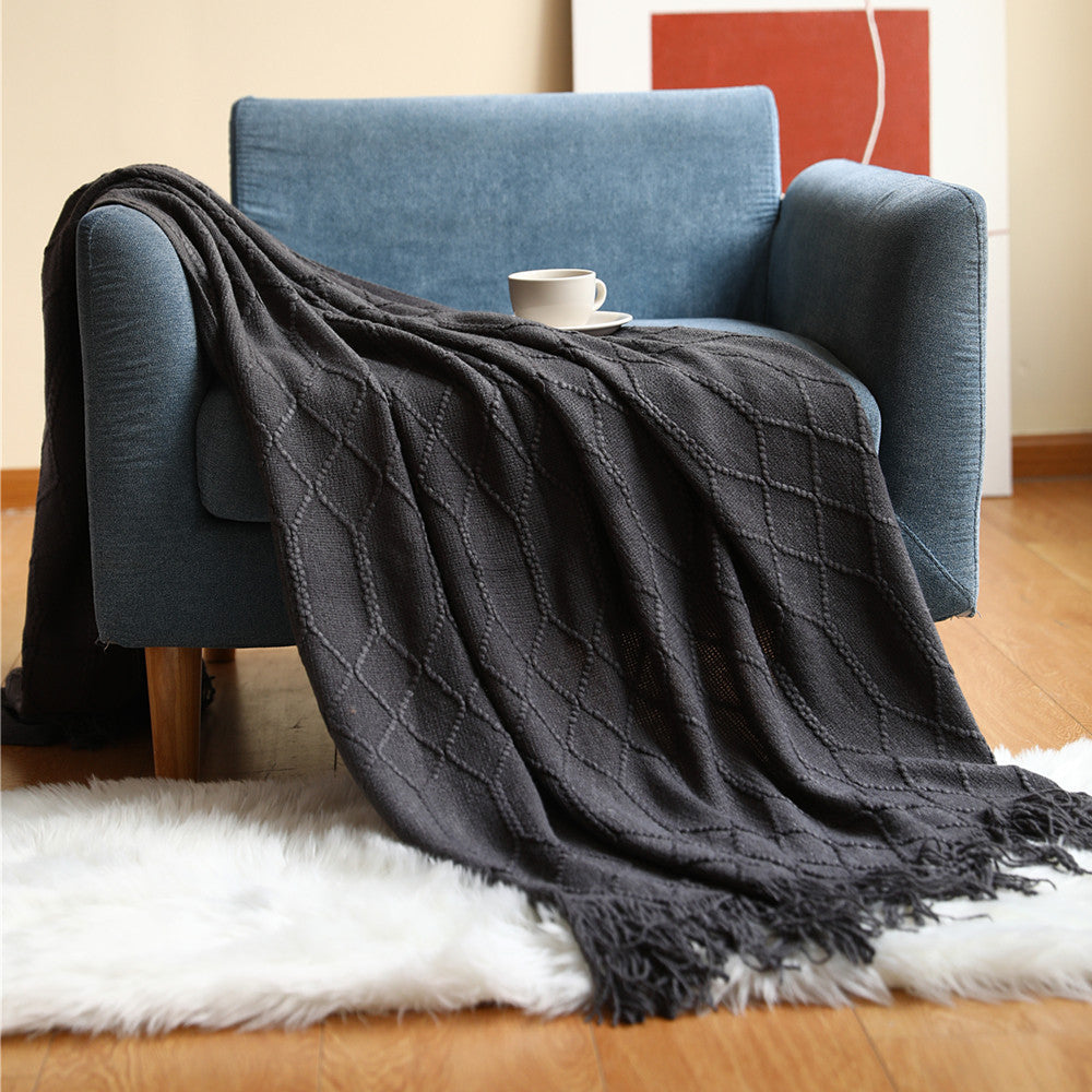Blush pink coral fleece throw blanket draped over a white armchair in a bedroom reading corner
