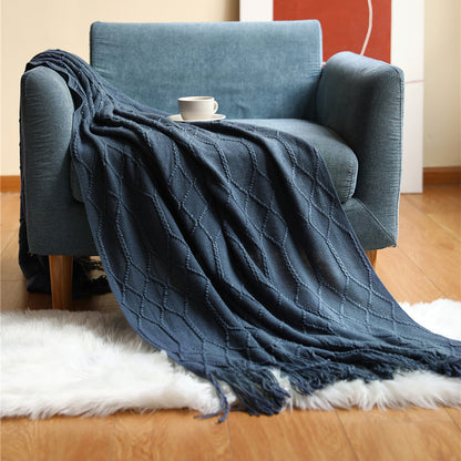 Yellow coral fleece throw blanket layered on a bed beside white pillows in a bright bedroom
