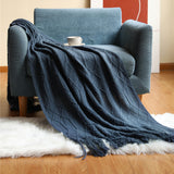 Yellow coral fleece throw blanket layered on a bed beside white pillows in a bright bedroom
