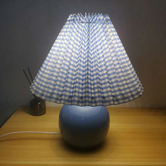 Decorative bedroom lamp with blue ceramic base and pleated fabric shade on side table

