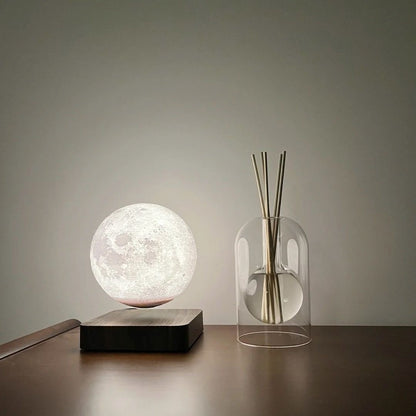 Levitating moon lamp on a table with a diffuser bottle in the background.