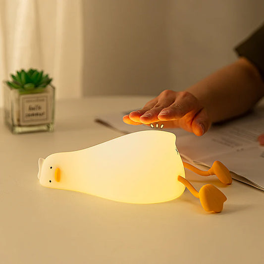 Flat duck night lamp glowing warm yellow light on bedside table