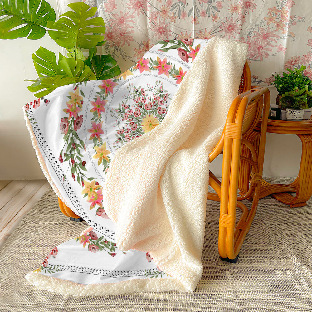 Soft botanical floral throw blanket draped over the back of a light gray sofa in a living room
