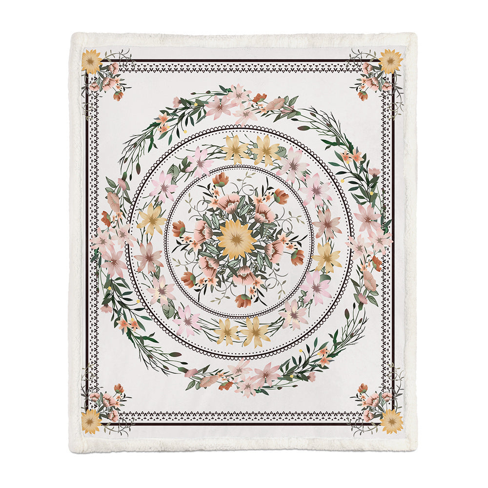 Large floral throw blanket layered at the foot of a white bed in a bright bedroom

