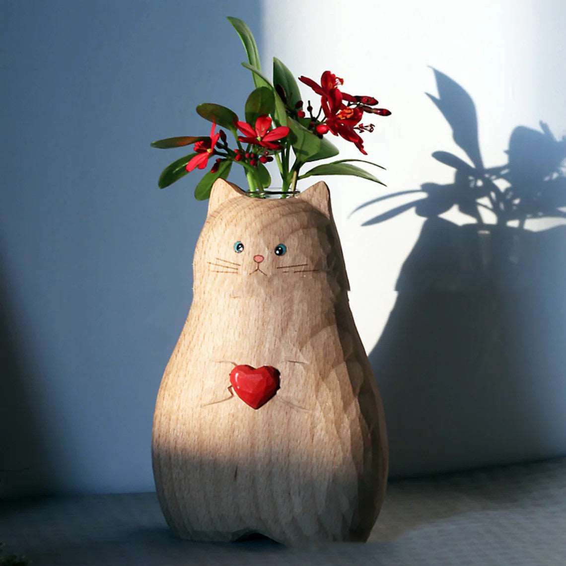 Wooden cat vase with heart design holding red flowers