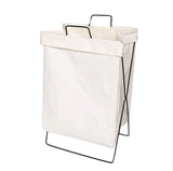 Collapsible fabric laundry basket standing upright in a bedroom corner holding a full load