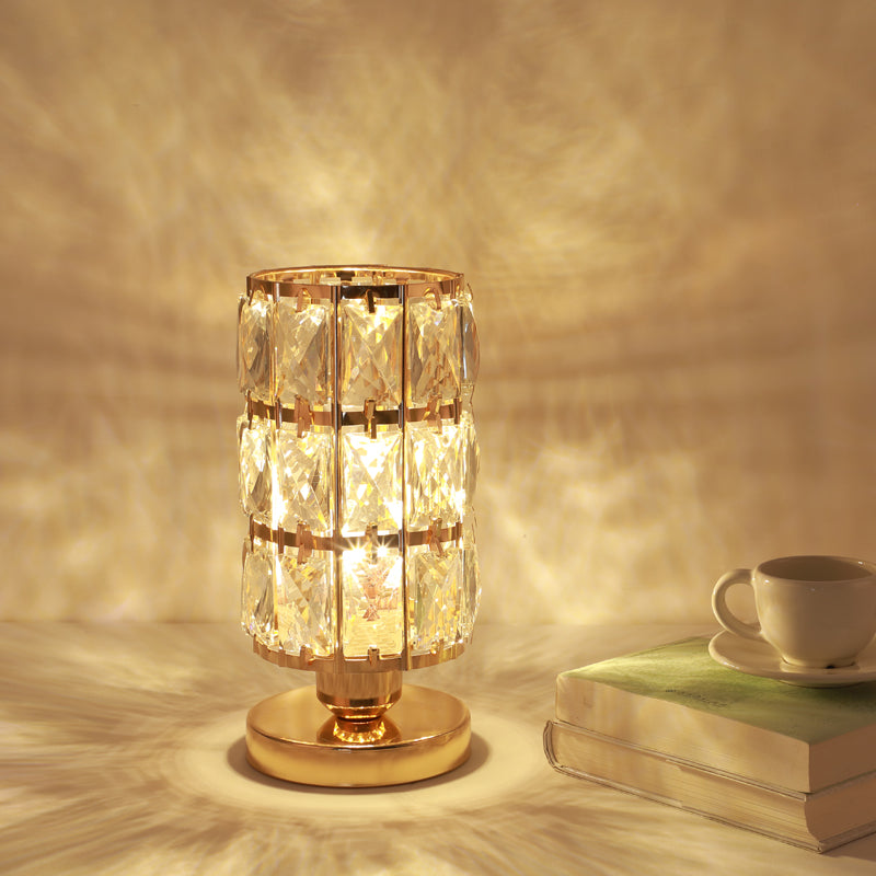 Gold crystal table lamp glowing on nightstand beside book and cup
