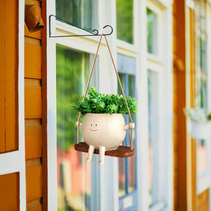 Hanging face planter hung on garden fence with plant