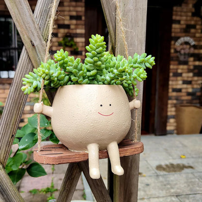 Hanging face planter with plants outdoors on wooden fence