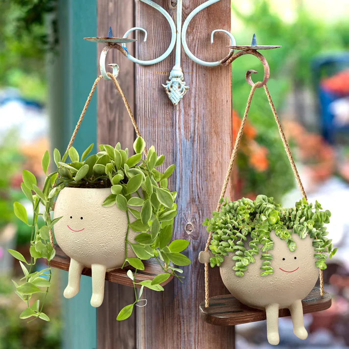 Multiple hanging face planters displayed on porch