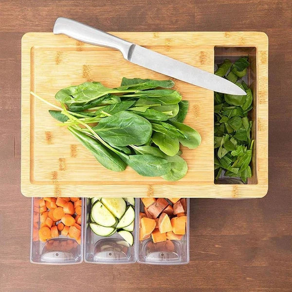 Top view of large bamboo chopping board with drawer filled with chopped fruits and vegetables