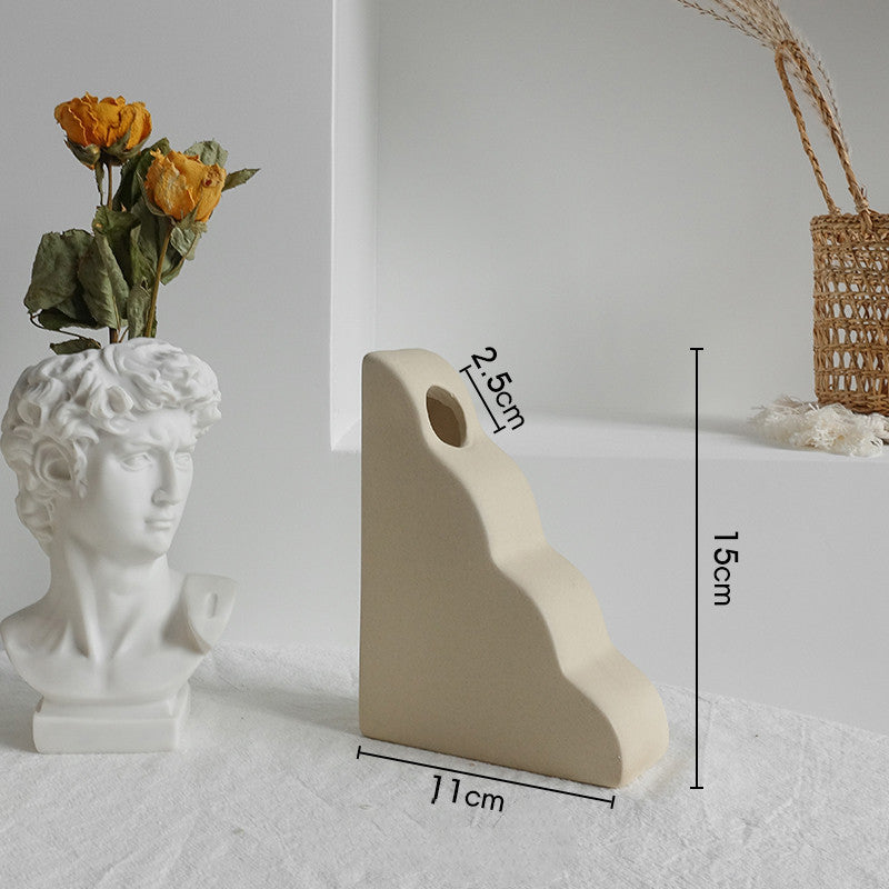 Matte ceramic vase styled on a bookshelf beside books and small decor in a Scandinavian room
