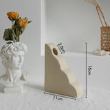 Matte ceramic vase styled on a bookshelf beside books and small decor in a Scandinavian room