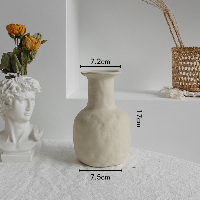 Matte ceramic vase holding cotton stems in a boho styled bedroom with neutral tones
