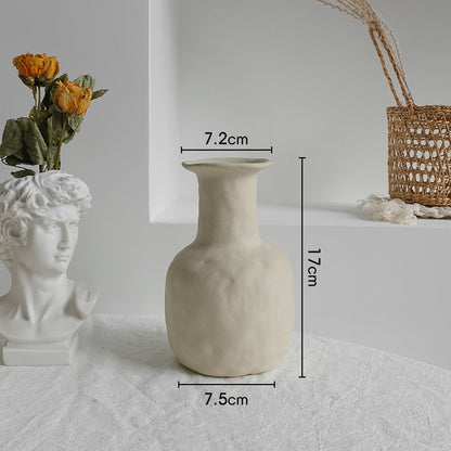 Matte ceramic vase holding cotton stems in a boho styled bedroom with neutral tones
