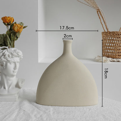 Matte ceramic vase with dried eucalyptus stems on a dining table in a minimalist room
