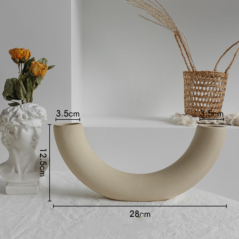 Hand holding a matte ceramic vase showing solid weight and unglazed surface texture
