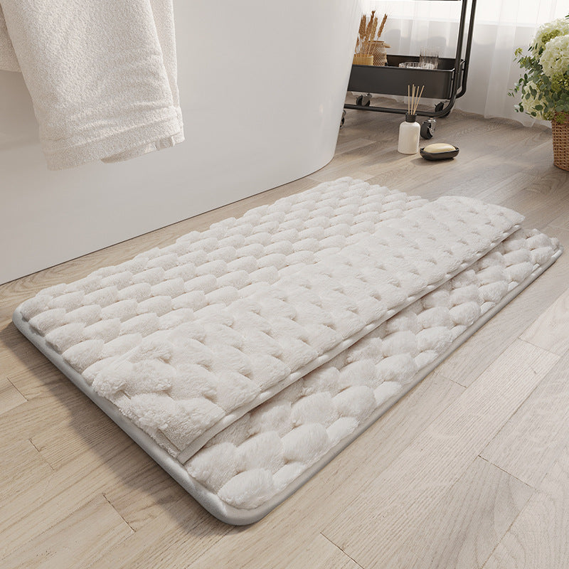 Gray memory foam bathroom mat placed at the exit of a shower on white tile floor
